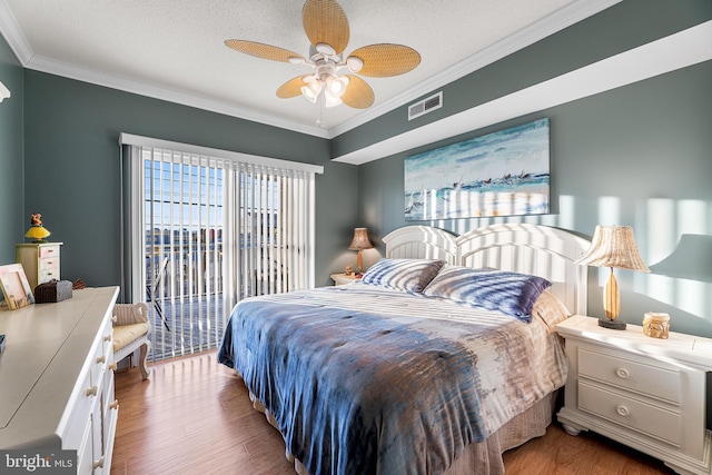 bedroom featuring a textured ceiling, ornamental molding, wood finished floors, and visible vents