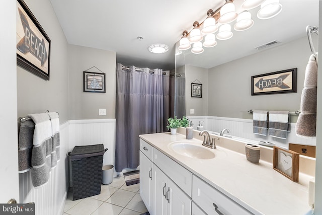 full bathroom with a wainscoted wall, visible vents, vanity, and tile patterned floors