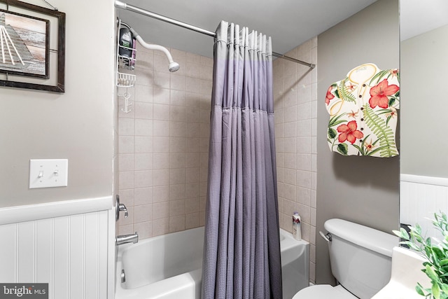 bathroom with toilet, shower / bath combination with curtain, and wainscoting