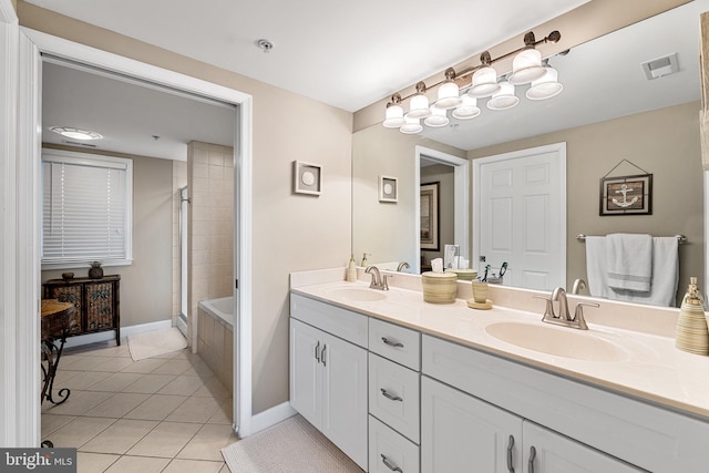 bathroom with a tub to relax in, tile patterned flooring, a sink, and visible vents