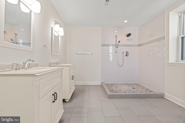 bathroom featuring walk in shower, two vanities, a sink, and baseboards