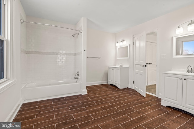 full bath with a sink, shower / washtub combination, two vanities, and wood tiled floor