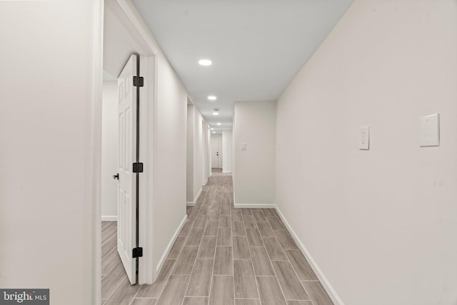 corridor featuring wood finish floors, recessed lighting, and baseboards