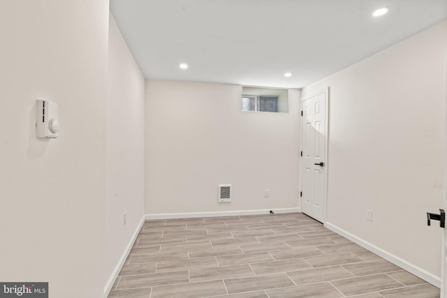 below grade area featuring baseboards, wood tiled floor, visible vents, and recessed lighting