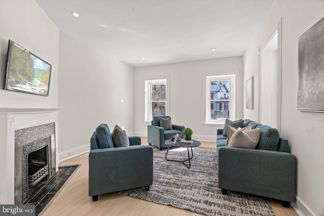 living area featuring wood finished floors, a fireplace with flush hearth, and baseboards