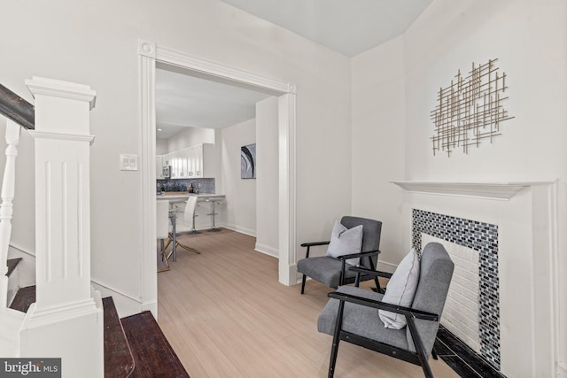 living area featuring baseboards, stairway, a tiled fireplace, and light wood-style floors