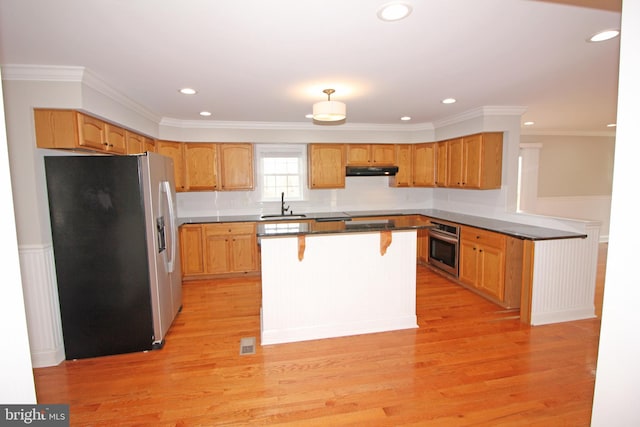 kitchen featuring stainless steel appliances, light wood-style floors, a sink, and under cabinet range hood