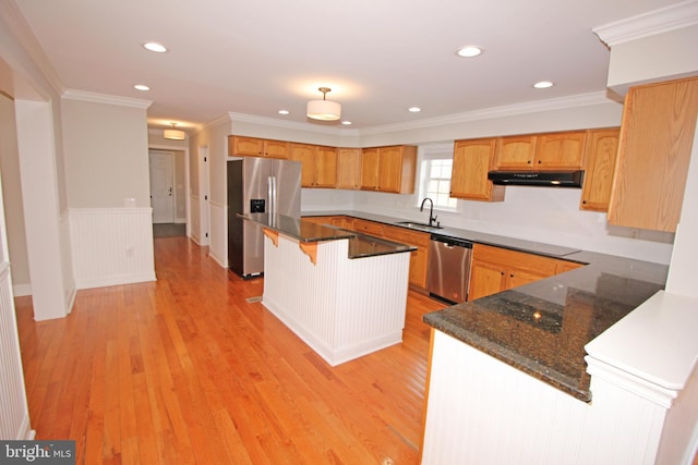 kitchen with under cabinet range hood, stainless steel appliances, a sink, light wood-type flooring, and crown molding