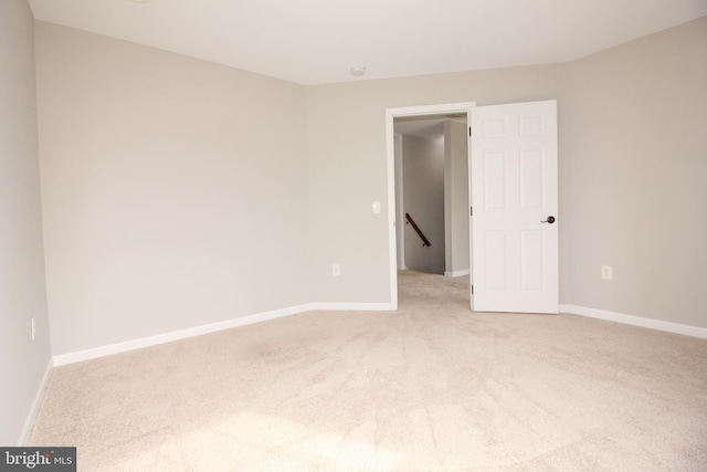 empty room featuring baseboards and light colored carpet