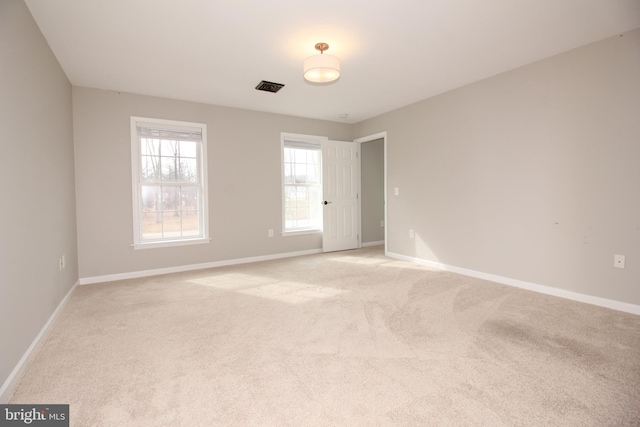 spare room with visible vents, light colored carpet, and baseboards