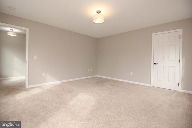 spare room with baseboards and light colored carpet