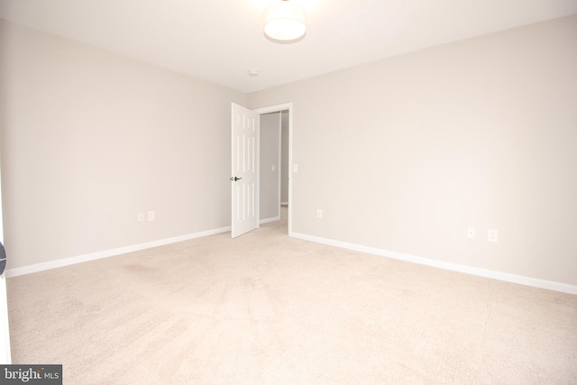 unfurnished room with light carpet and baseboards