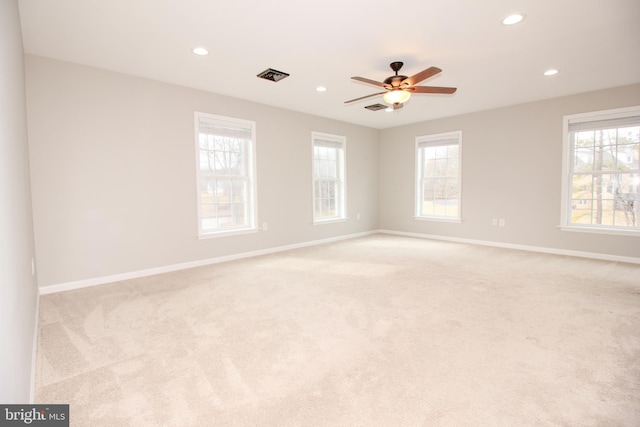 spare room with light carpet, a healthy amount of sunlight, visible vents, and baseboards