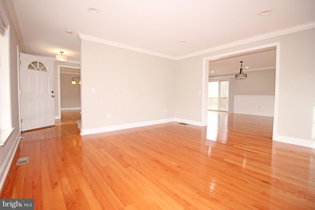 unfurnished living room with light wood-style floors, baseboards, visible vents, and ornamental molding