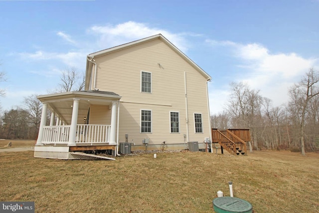 rear view of property with cooling unit, a porch, and a lawn