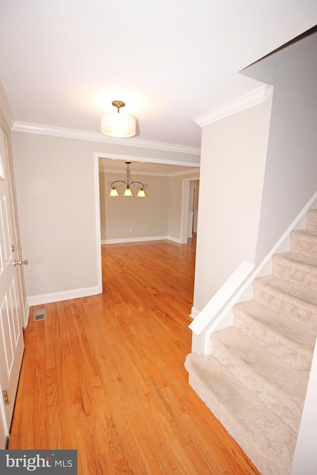 interior space with visible vents, baseboards, stairs, light wood finished floors, and crown molding