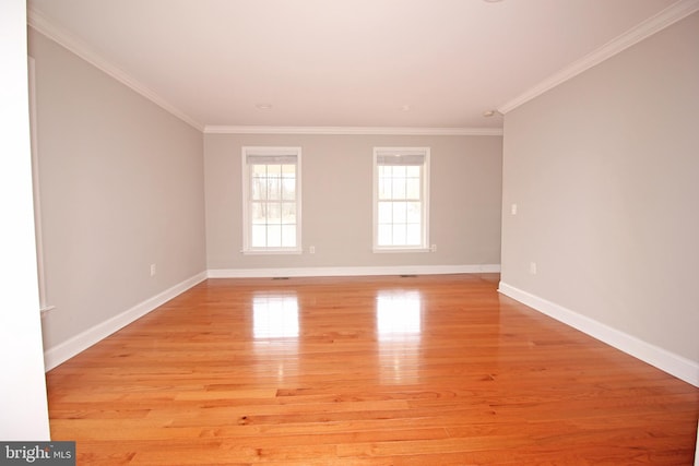 empty room featuring light wood finished floors, baseboards, and ornamental molding