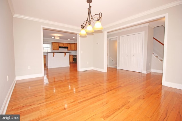 unfurnished dining area with baseboards, light wood-type flooring, a chandelier, and crown molding