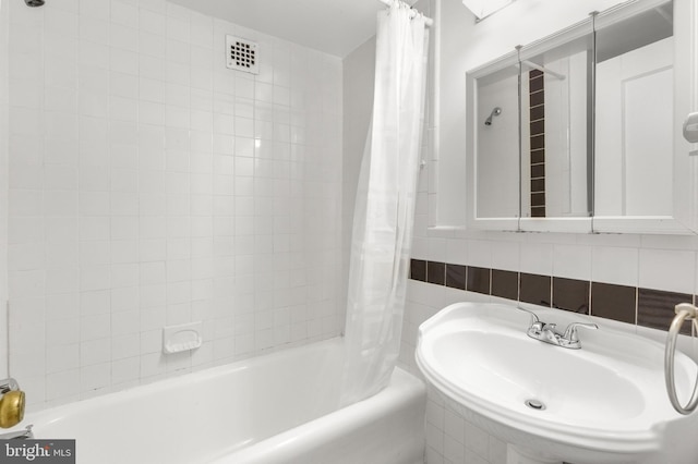 bathroom featuring a sink, shower / bath combo with shower curtain, and visible vents