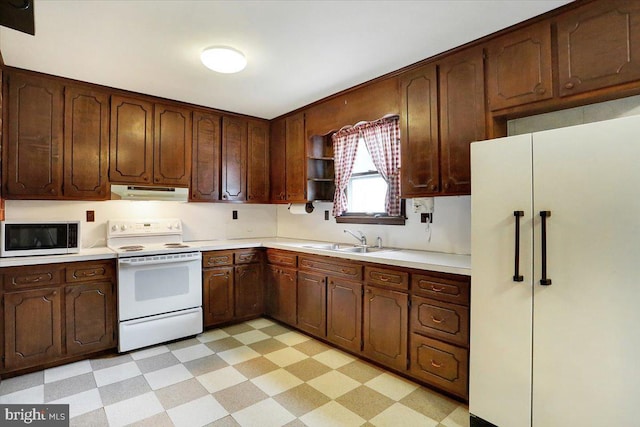 kitchen with white appliances, a sink, under cabinet range hood, and light floors