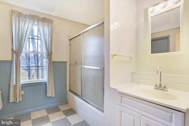 bathroom with a wainscoted wall, shower / bath combination with glass door, vanity, and tile patterned floors