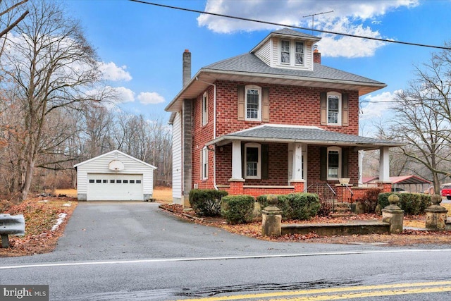 traditional style home featuring an outbuilding, covered porch, brick siding, a detached garage, and roof with shingles