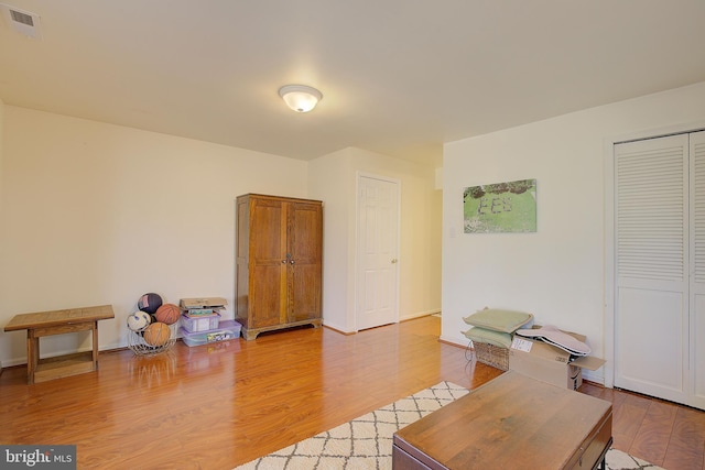 office space featuring baseboards, visible vents, and light wood finished floors