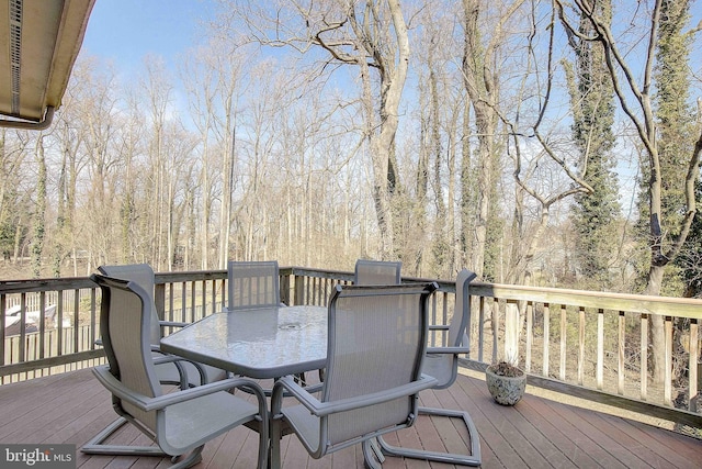 deck with outdoor dining area and a view of trees