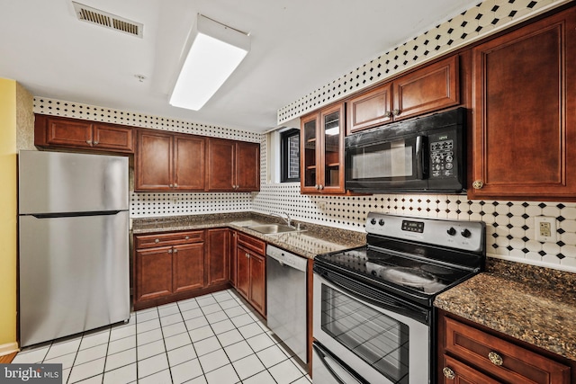 kitchen with light tile patterned floors, tasteful backsplash, visible vents, glass insert cabinets, and stainless steel appliances