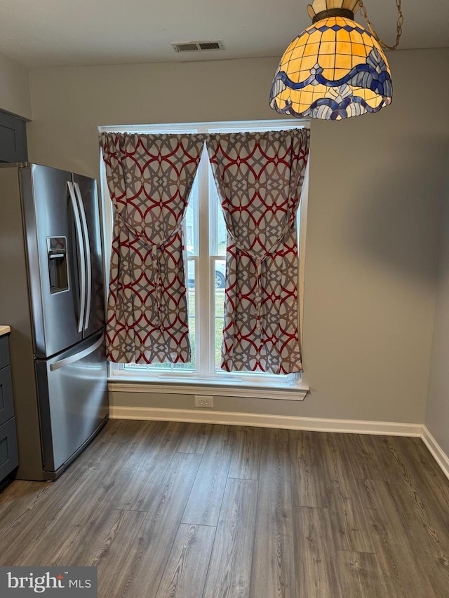 unfurnished dining area featuring baseboards, visible vents, and wood finished floors