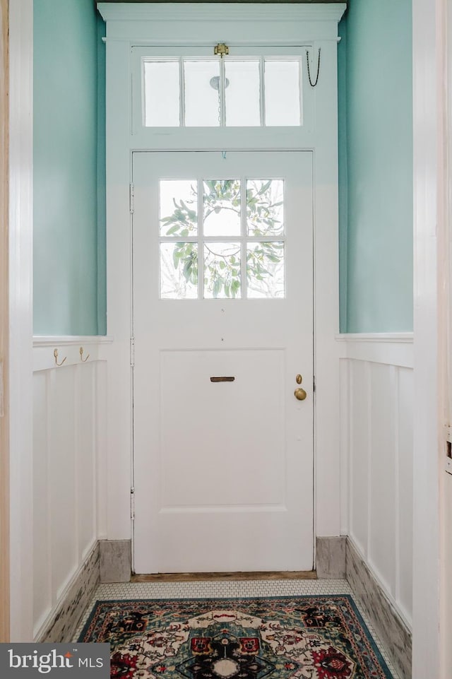 doorway to outside featuring wainscoting and plenty of natural light