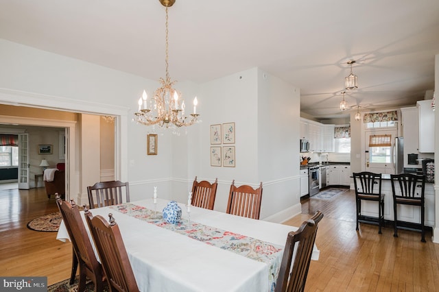 dining area featuring wood-type flooring and an inviting chandelier