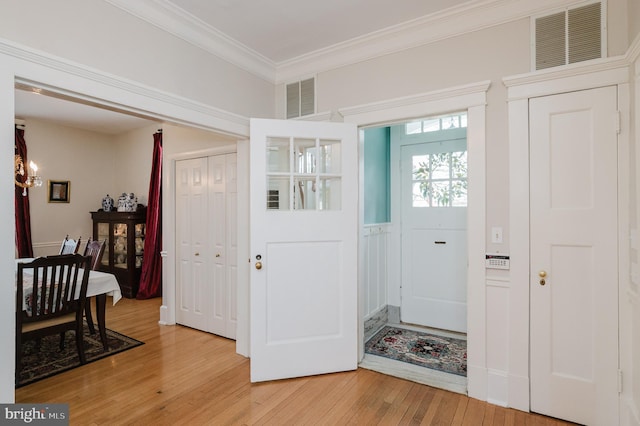 entrance foyer with visible vents, light wood-style flooring, and ornamental molding