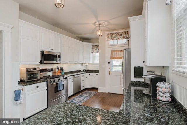 kitchen with dark stone countertops, white cabinetry, a sink, and stainless steel appliances