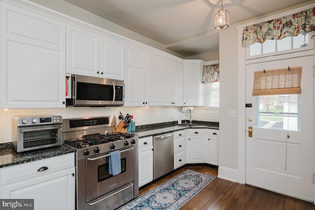 kitchen with white cabinets, a sink, stainless steel appliances, and dark wood-type flooring