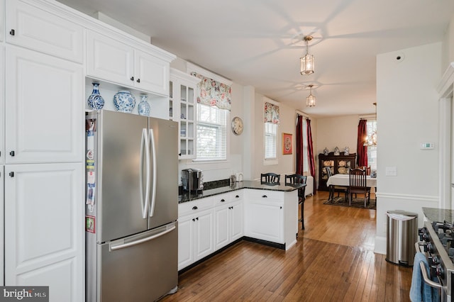 kitchen with dark wood finished floors, appliances with stainless steel finishes, glass insert cabinets, and a wealth of natural light
