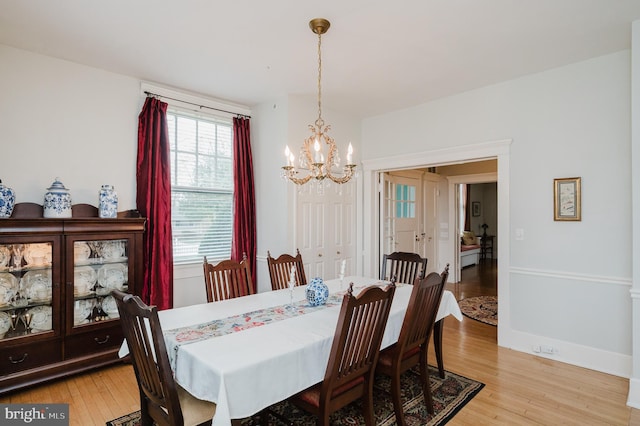 dining space featuring a notable chandelier, baseboards, and light wood finished floors
