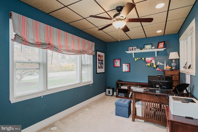 carpeted office space with a ceiling fan, baseboards, and a paneled ceiling