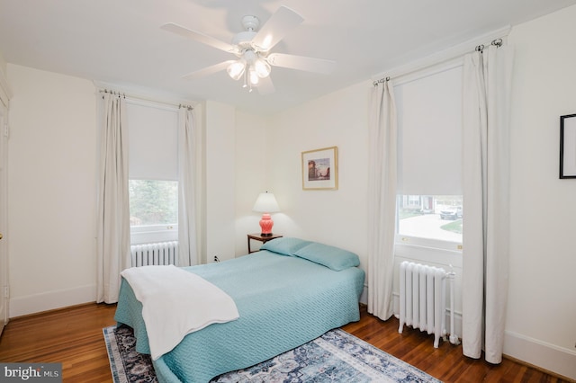 bedroom with radiator heating unit, a ceiling fan, baseboards, and wood finished floors