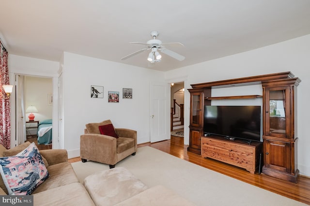 living area featuring baseboards, stairs, ceiling fan, wood finished floors, and arched walkways