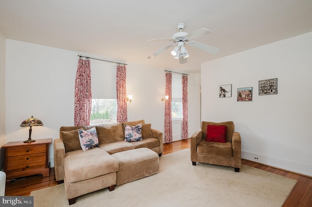 living area featuring baseboards, wood finished floors, and a ceiling fan