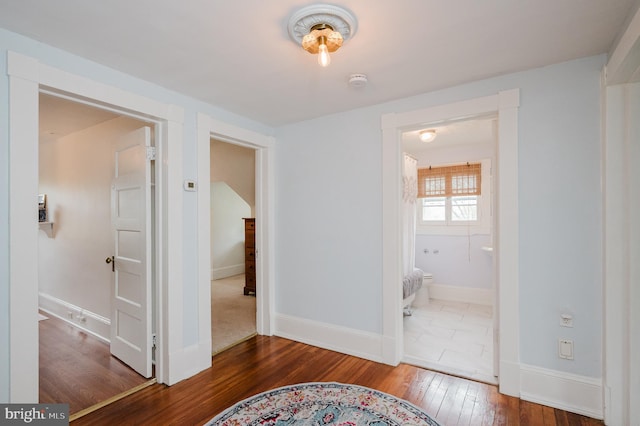 hallway featuring baseboards and hardwood / wood-style flooring