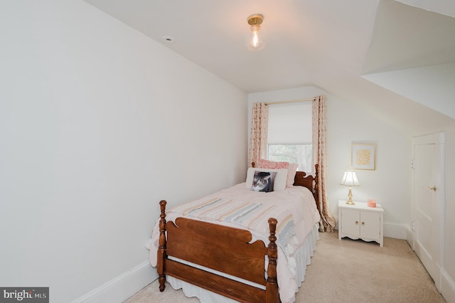 bedroom featuring baseboards, lofted ceiling, and light carpet