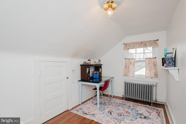 home office featuring baseboards, wood finished floors, vaulted ceiling, and radiator