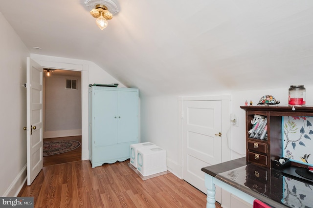 additional living space featuring light wood-style flooring, baseboards, vaulted ceiling, and visible vents