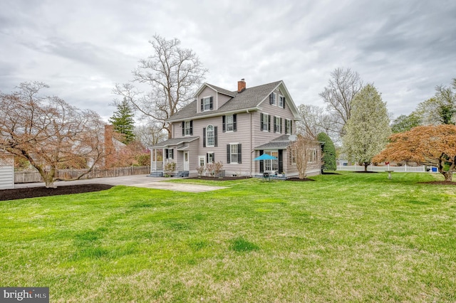 view of front of property featuring fence, a chimney, a front yard, a shingled roof, and a patio area