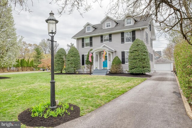view of front of house featuring a detached garage, a front lawn, and an outdoor structure