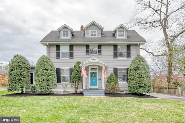 view of front of home featuring a chimney, fence, a front lawn, and a shingled roof