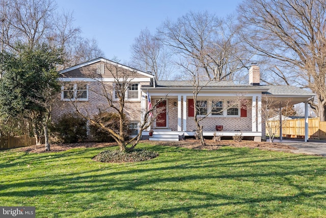 tri-level home with brick siding, a carport, a front yard, and fence