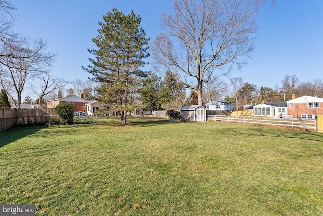 view of yard with a storage shed, a fenced backyard, and an outdoor structure